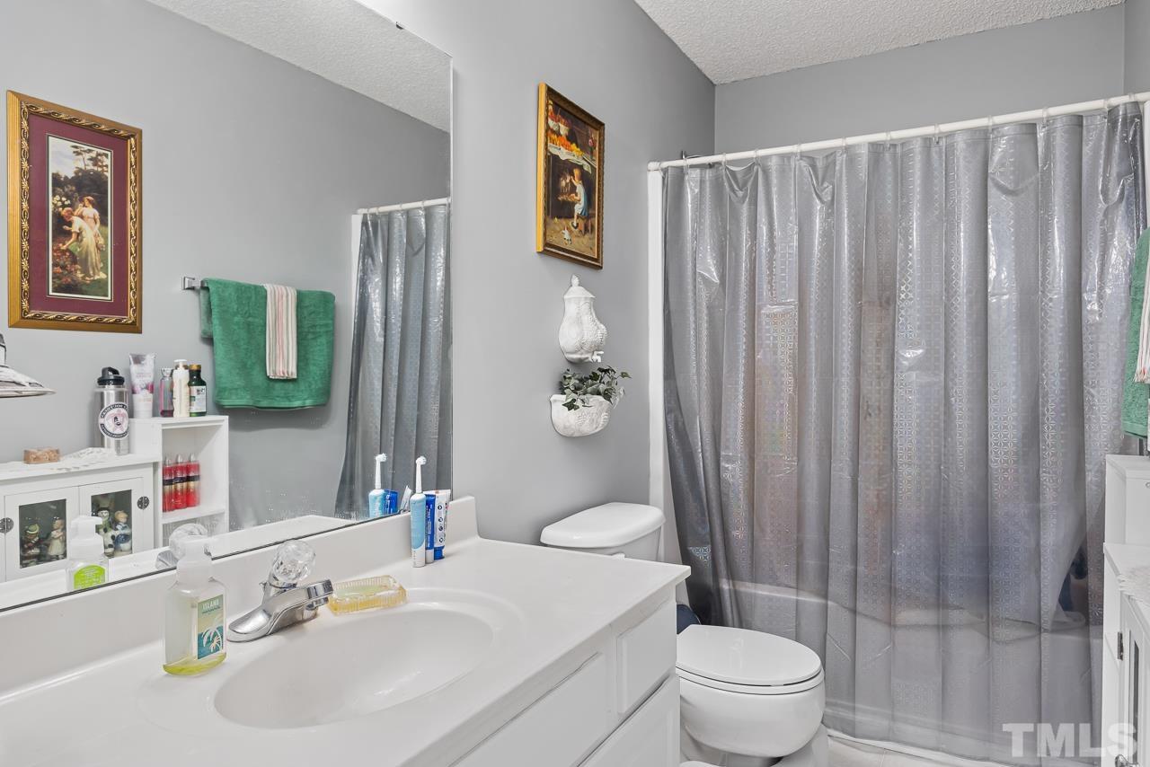 229 Roping Horn Way Willow Spring, NC 27592 - Photo 22 of 30 a bathroom with a sink a toilet and shower curtain