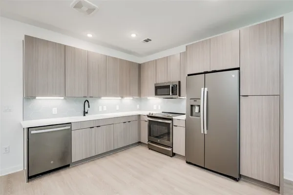 a kitchen with stainless steel appliances granite countertop a refrigerator sink and stove