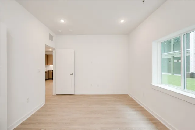 an empty room with wooden floor and windows