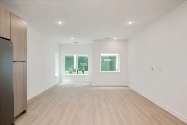 an empty room with wooden floor and windows