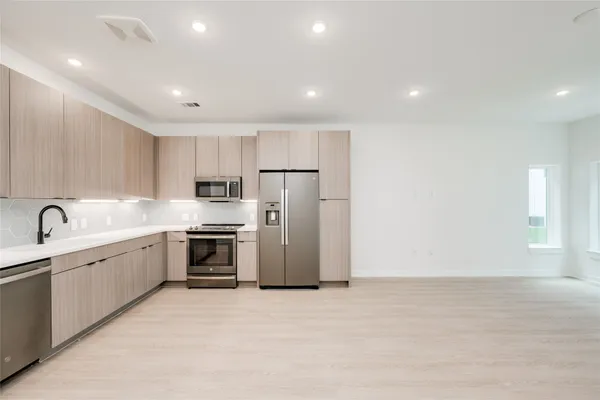 a large kitchen with stainless steel appliances granite countertop a stove a sink and a refrigerator