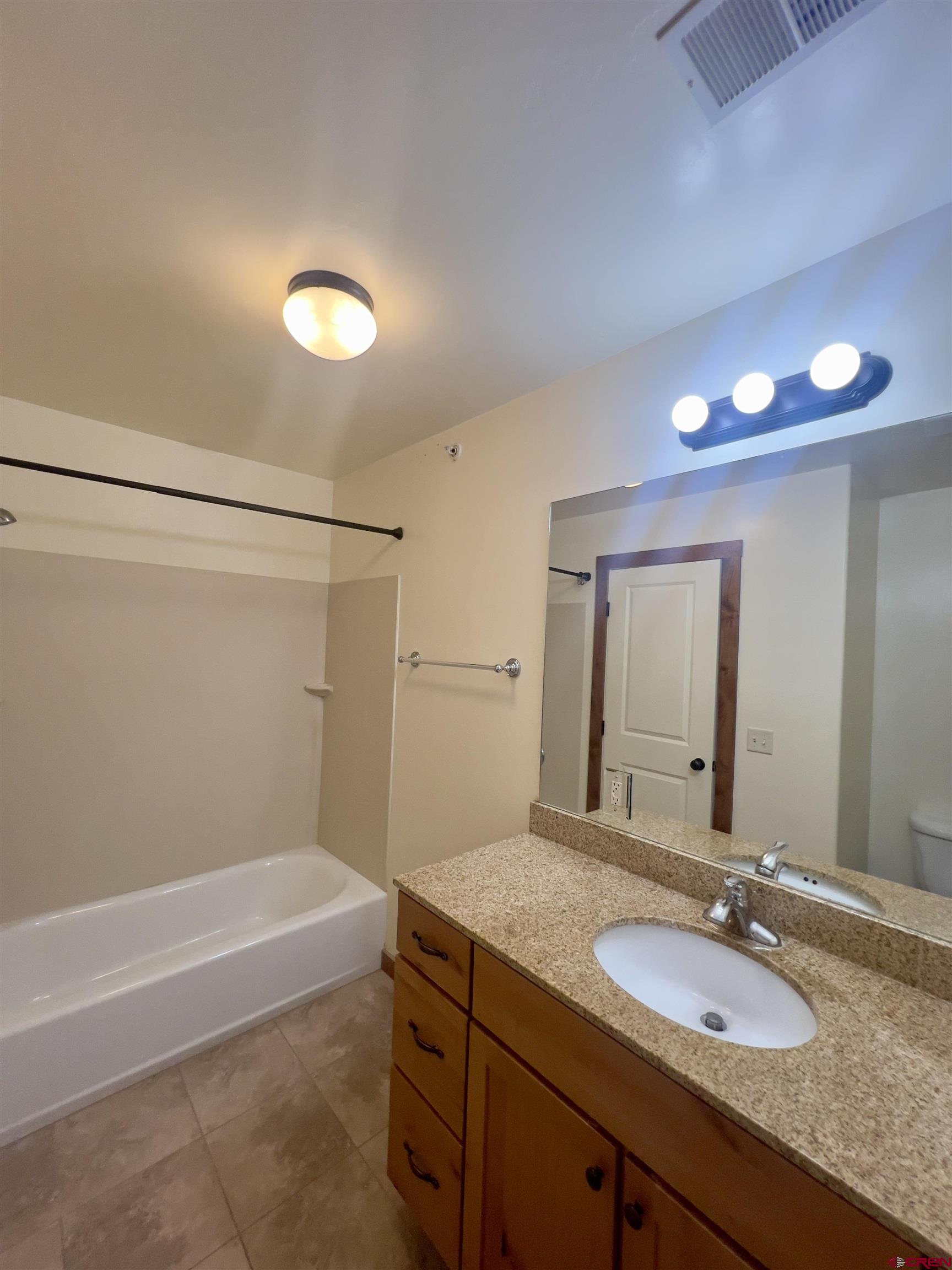 540 Redcliff Circle, Unit E 203 Ridgway, CO 81432 - Photo 21 of 36 a bathroom with a granite countertop bathtub a sink and a mirror