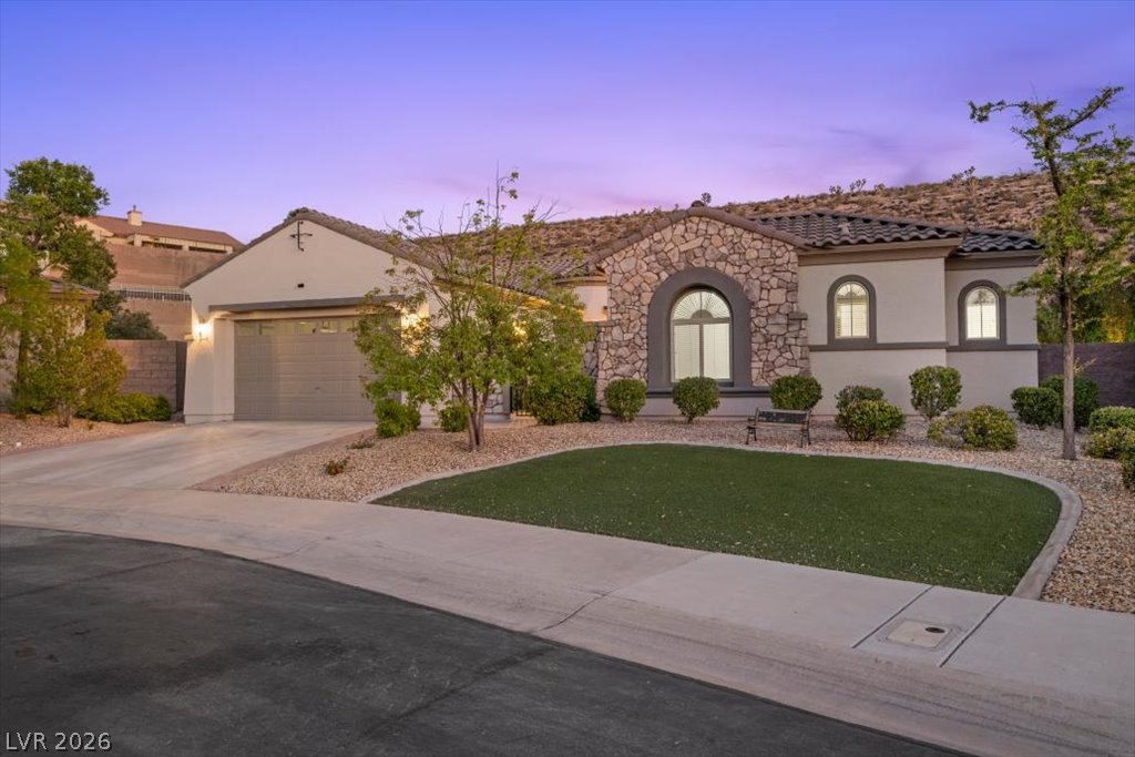 2125 De Rouge Avenue Henderson, NV 89044 - Photo 24 of 96 A desert-modern residence with a stone facade, arched windows, and a meticulously landscaped front yard.