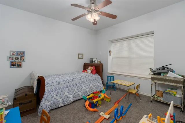 a bedroom with furniture and a chandelier fan