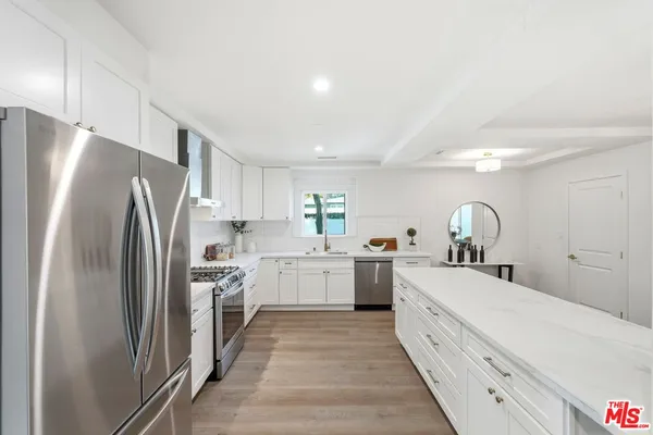 a kitchen with white cabinets and stainless steel appliances