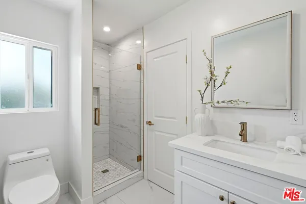 a bathroom with a shower sink vanity mirror and toilet