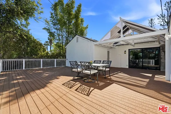a view of a patio with table and chairs with wooden floor and fence