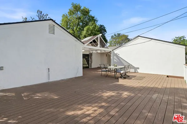 a roof deck with table and chairs and wooden floor