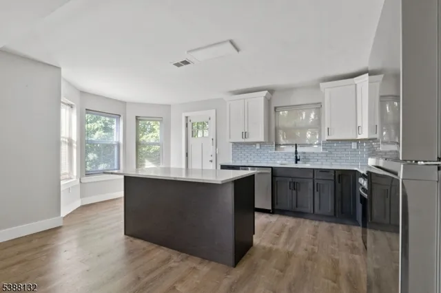 a large kitchen with kitchen island granite countertop a stove top oven sink and cabinets