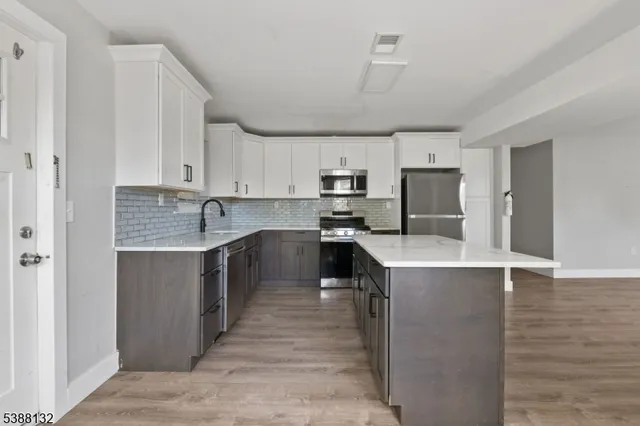 a kitchen with kitchen island a counter top space a sink stainless steel appliances and cabinets