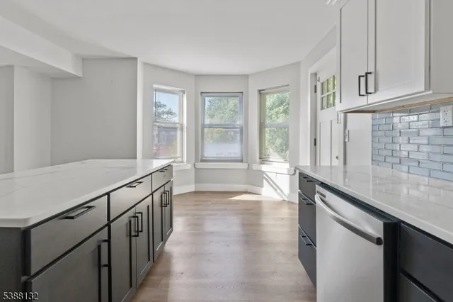 a view of a kitchen with granite countertop a sink and dishwasher a oven with white cabinets