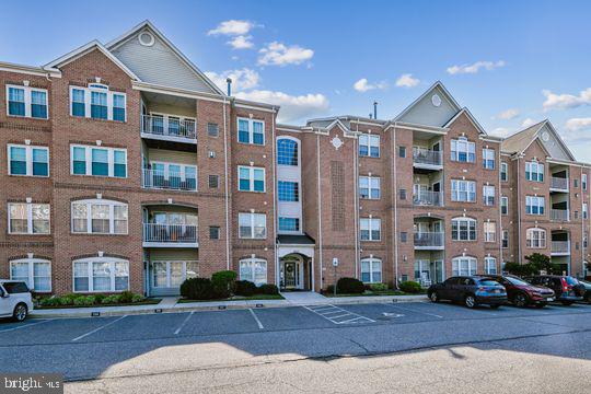 9511 Kingscroft Terrace, Unit 9511F Perry Hall, MD 21128 - Photo 2 of 38 a front view of a building with lot of cars and trees