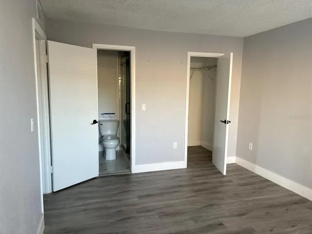 a view of an empty room with wooden floor and closet
