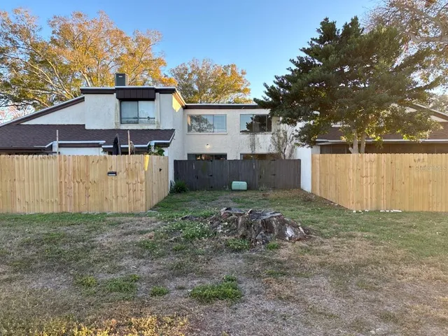 a view of a house with a yard and a large tree
