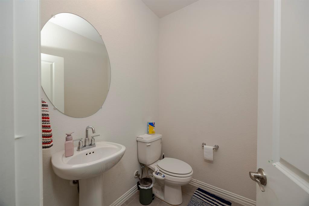 495 Fox Ridge Drive Princeton, TX 75407 - Photo 17 of 31 Pedestal sink with chrome faucet, oval wall mirror, and neutral wall tones