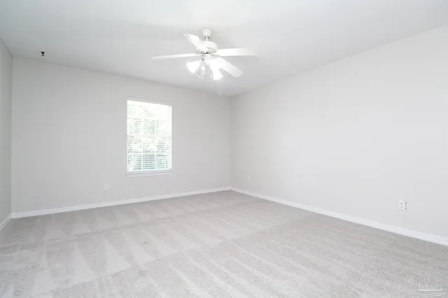 an empty room with windows and chandelier fan