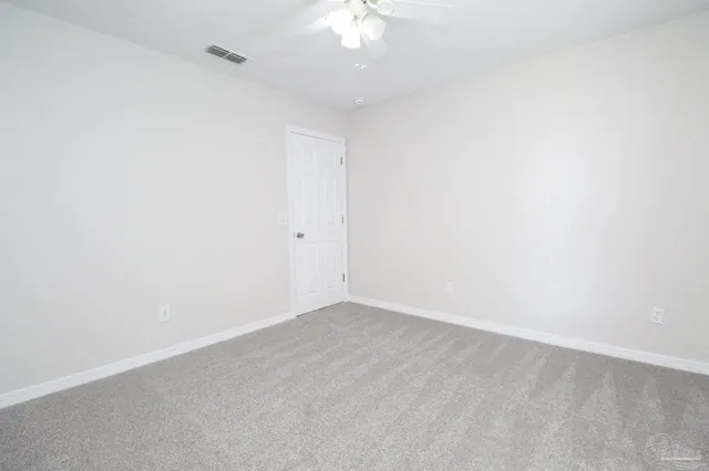 an empty room with a chandelier fan and closet area