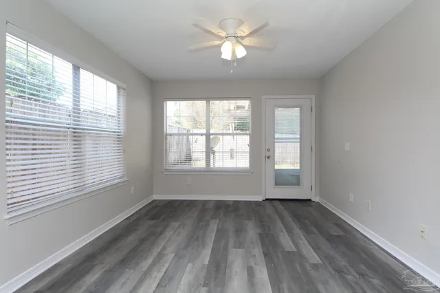 a view of empty room with wooden floor and fan