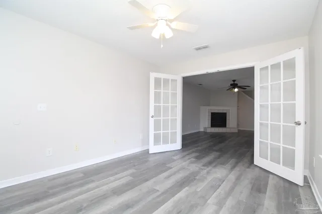 an empty room with wooden floor closet and windows