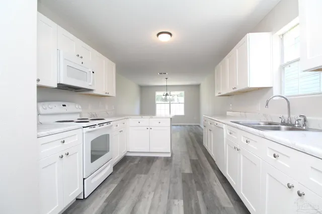 a kitchen with granite countertop white cabinets and white appliances
