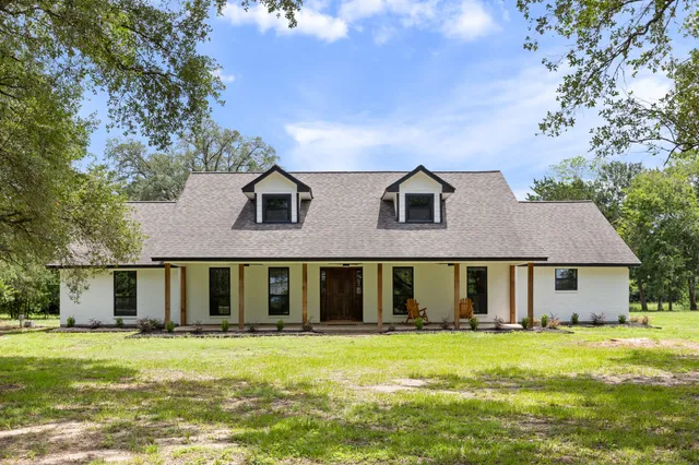 a view of a big house with a big yard and large trees