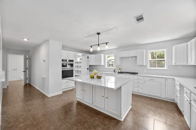 a kitchen with kitchen island white cabinets and refrigerator