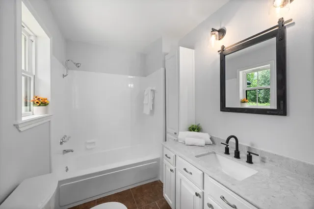 a bathroom with a bathtub sink vanity mirror and toilet