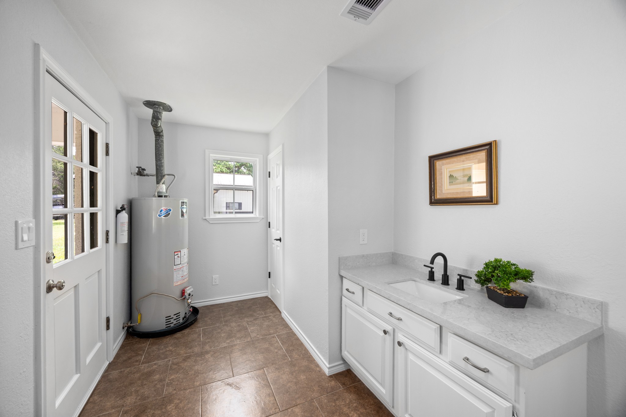 10209 Oberrender Road Needville, TX 77461 - Photo 31 of 50 Utility room features a sink, storage, counterspace, and a doorway leading to the garage and backyard.