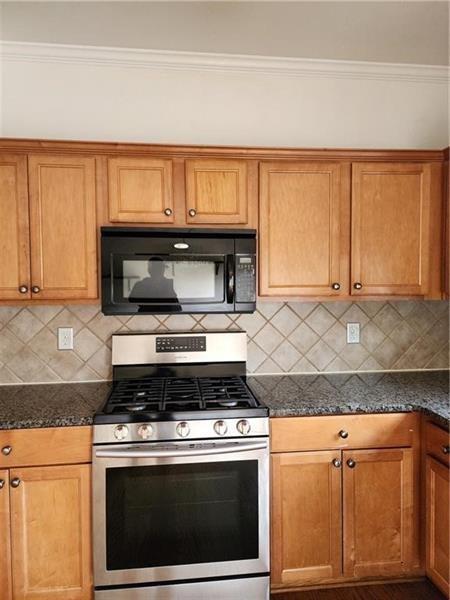 5079 Sherwood Way Cumming, GA 30040 - Photo 7 of 14 a kitchen with granite countertop a stove top oven microwave and cabinets