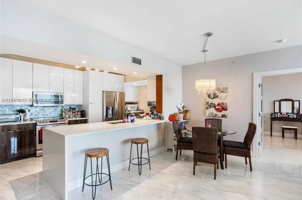 a room with stainless steel appliances kitchen island granite countertop furniture and a dining table