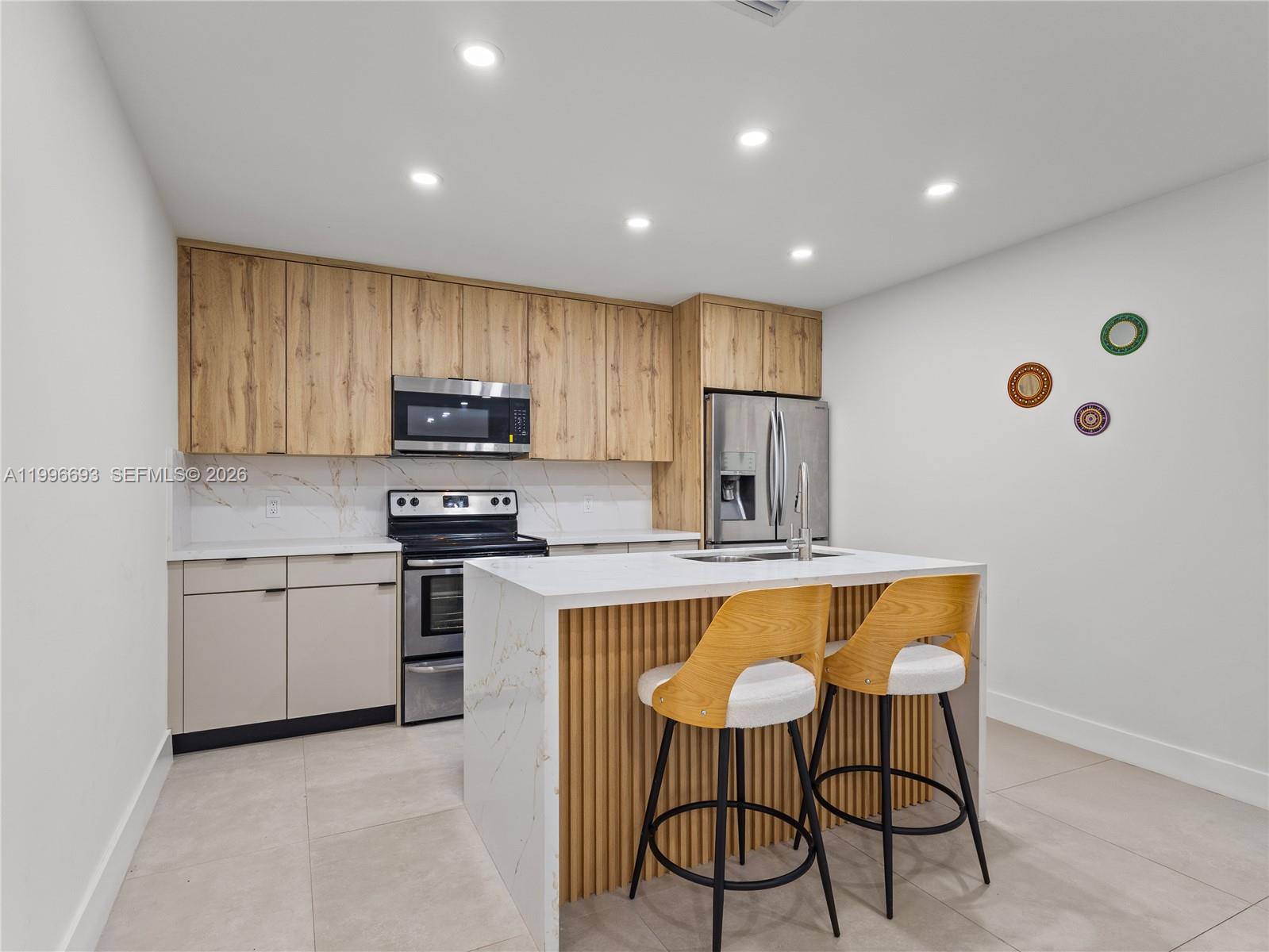 10017 Southwest 23rd Terrace Miami, FL 33165 - Photo 11 of 25 a kitchen with kitchen island granite countertop wooden cabinets a stove a sink and a refrigerator