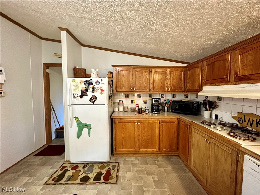 9400 Chalon Road Scio, OH 43988 - Photo 15 of 43 Kitchen with white appliances, under cabinet range hood, vaulted ceiling, backsplash, and crown molding