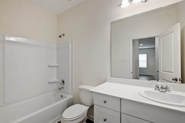a bathroom with a bathtub shower sink mirror vanity and toilet