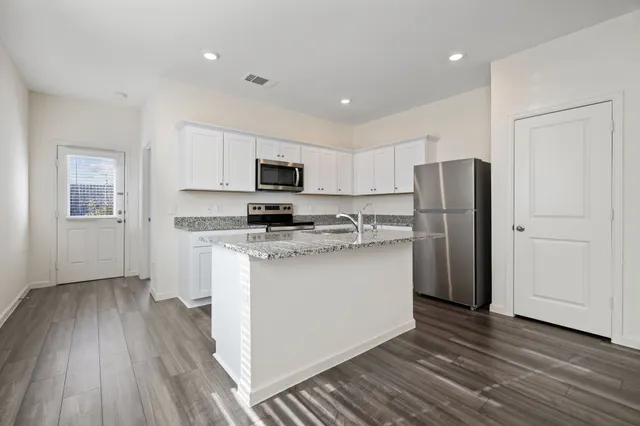 a kitchen with a refrigerator a stove top oven a sink and dishwasher with wooden floor