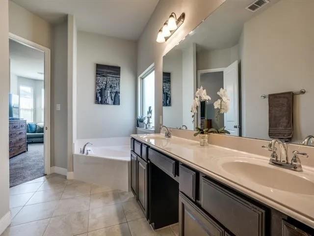 321 Valentino Way Grand Prairie, TX 75052 - Photo 19 of 24 a bathroom with a granite countertop sink a large mirror and a bathtub