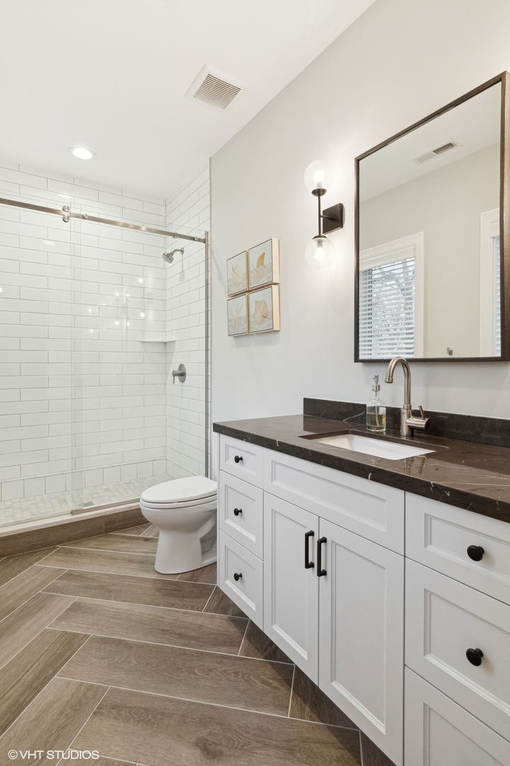 1401 Maple Avenue Wilmette, IL 60091 - Photo 28 of 46 a bathroom with a granite countertop sink a toilet and a mirror