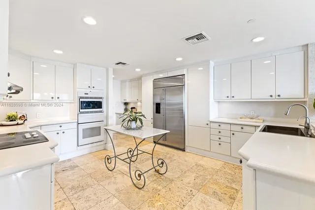 a kitchen with white cabinets and dining table chairs