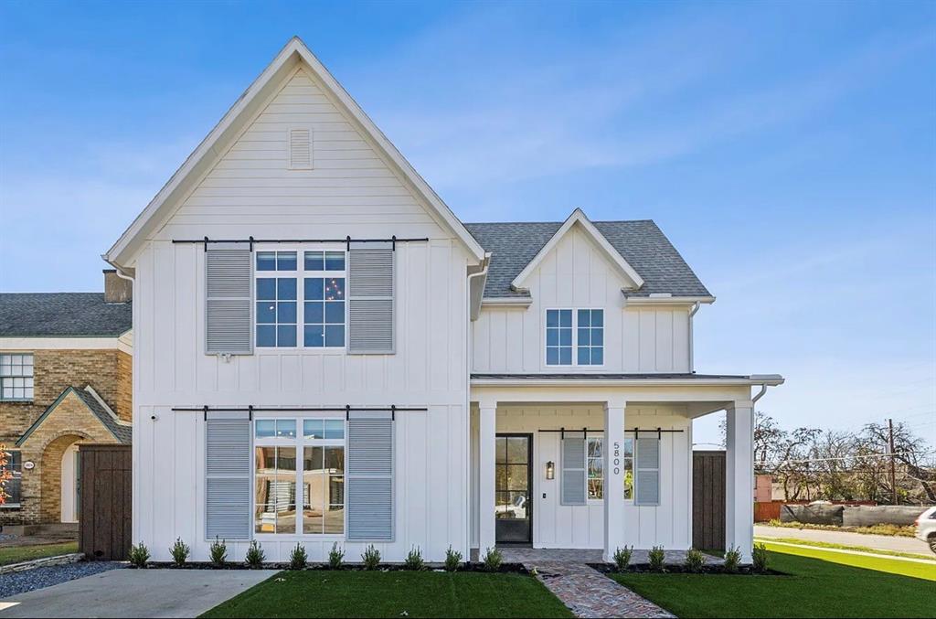 This property features a crisp white exterior with vertical board and batten siding, dark gray shutters, and a gray shingled roof