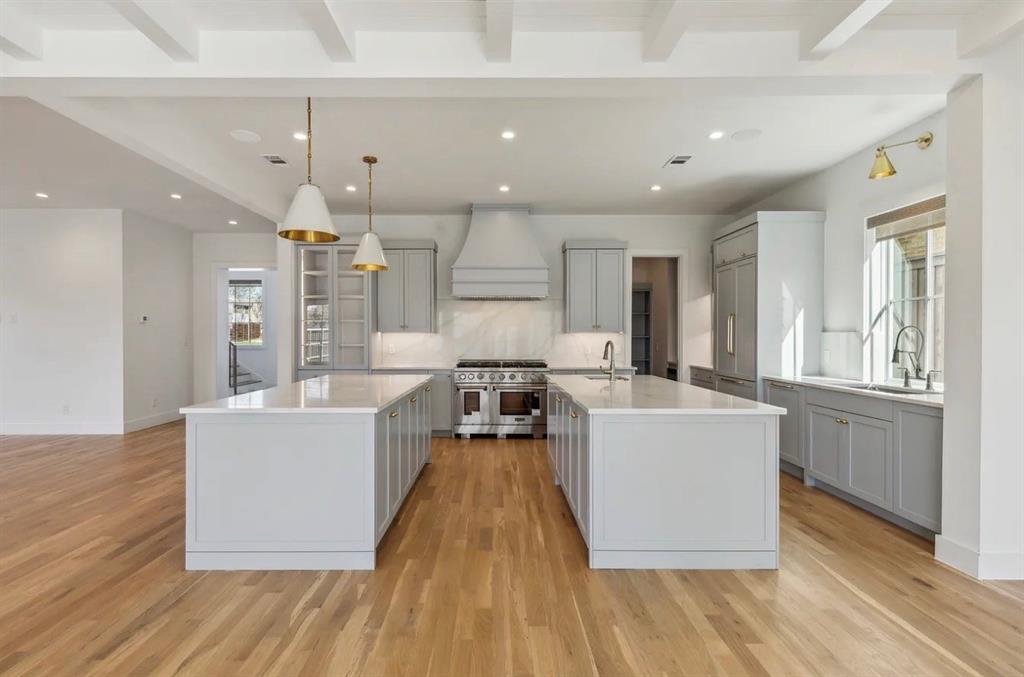 5800 Goodwin Avenue Dallas, TX 75206 - Photo 14 of 39 The kitchen features two islands with white countertops, light grey cabinetry, and stainless steel appliances, including a range oven and refrigerator