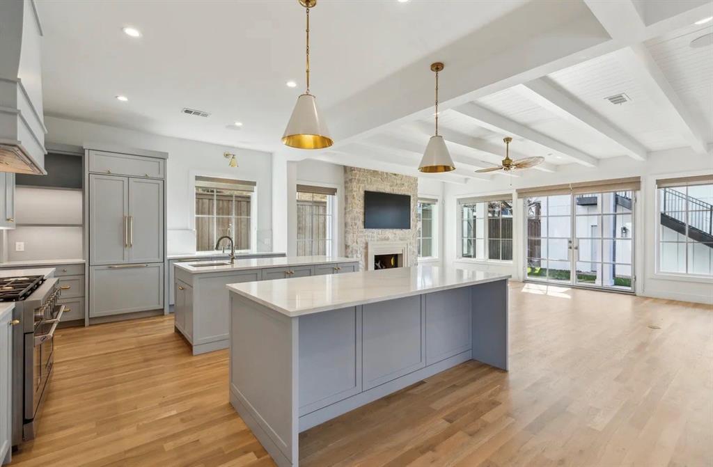 5800 Goodwin Avenue Dallas, TX 75206 - Photo 15 of 39 The open concept living area features light wood flooring, two kitchen islands with light countertops, and a stone-clad fireplace