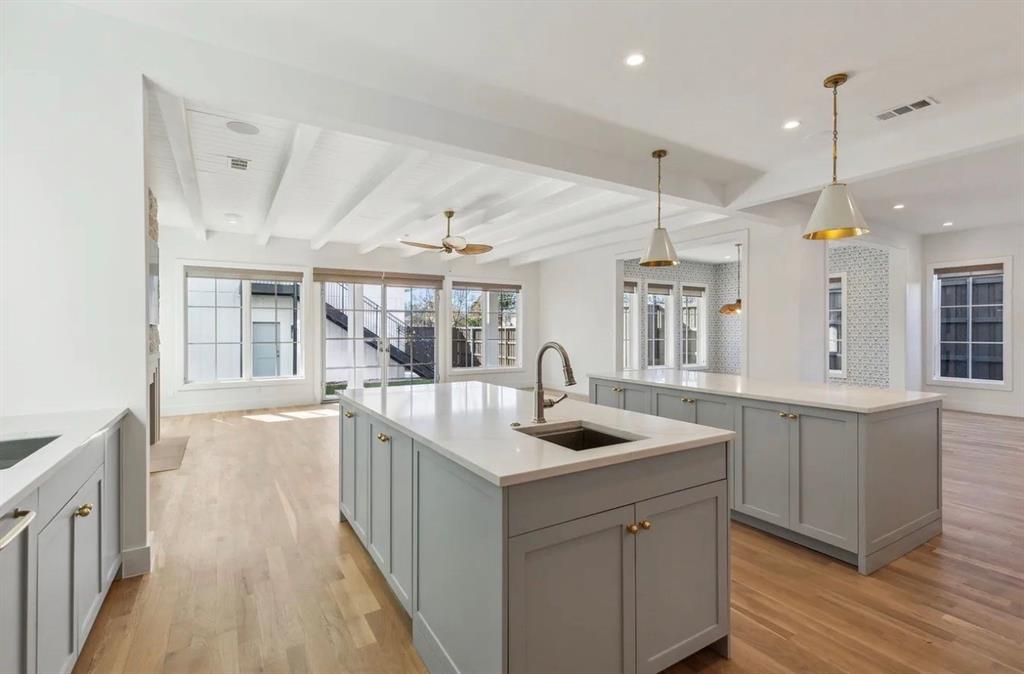 5800 Goodwin Avenue Dallas, TX 75206 - Photo 16 of 39 The property features an open concept kitchen and living area, complete with light wood flooring, two kitchen islands with light countertops and cabinetry, and a ceiling fan