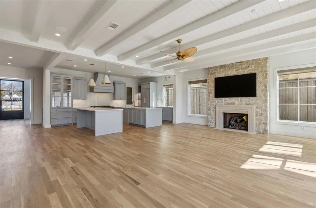 5800 Goodwin Avenue Dallas, TX 75206 - Photo 18 of 39 Expansive living area featuring light wood flooring, a stone fireplace, and exposed ceiling beams