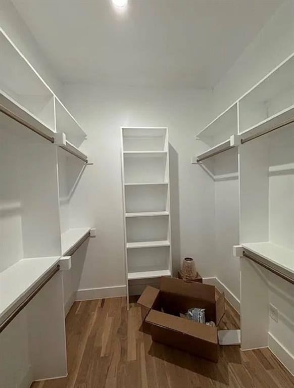 5800 Goodwin Avenue Dallas, TX 75206 - Photo 20 of 39 Walk-in closet featuring extensive built-in shelving and hanging rods, a central shelving unit, and hardwood flooring