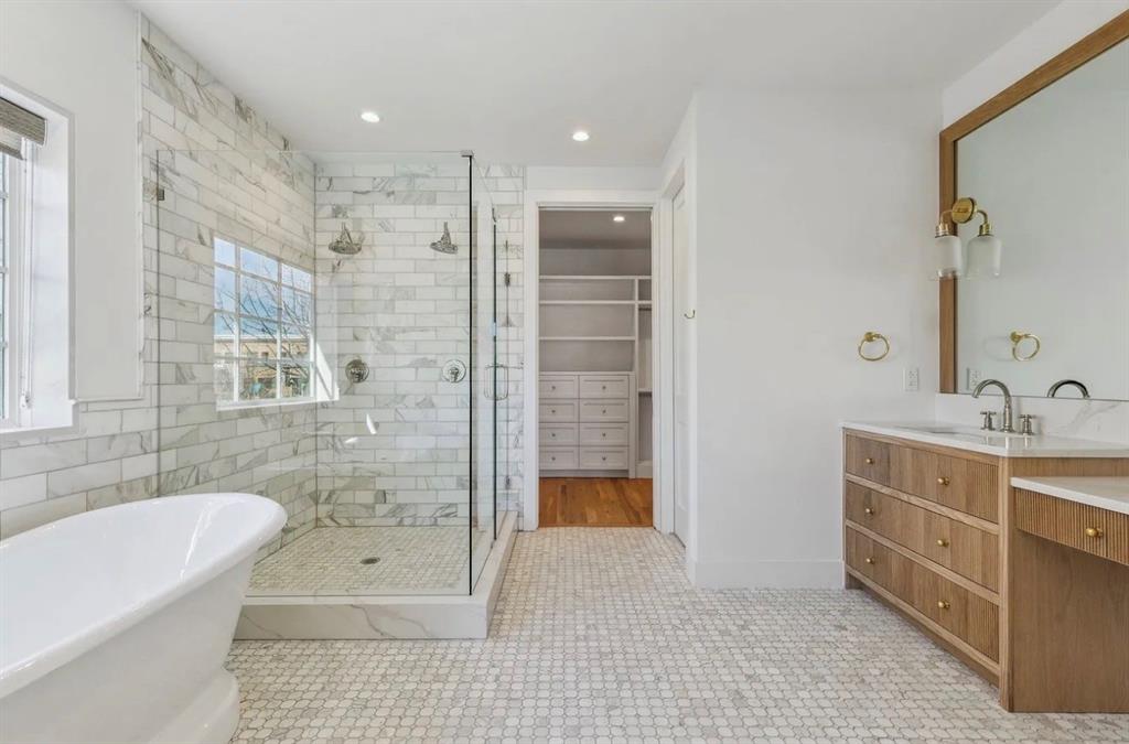 5800 Goodwin Avenue Dallas, TX 75206 - Photo 27 of 39 The primary bathroom features a freestanding bathtub, a walk-in shower with subway tile, and a vanity with a white countertop and a large mirror