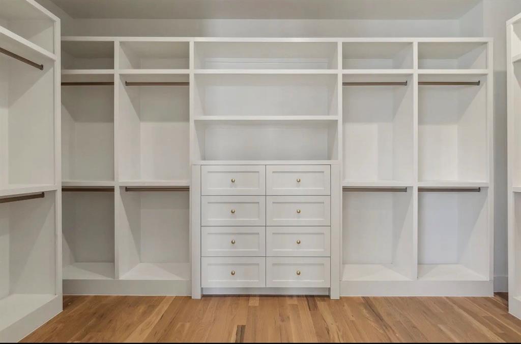 5800 Goodwin Avenue Dallas, TX 75206 - Photo 29 of 39 The property features a custom closet with white built-in shelving, hanging rods, and a central dresser unit with drawers