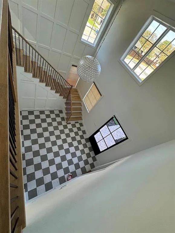 5800 Goodwin Avenue Dallas, TX 75206 - Photo 3 of 39 The property features a grand entryway with a checkered floor, a broad staircase with wooden handrails and dark balusters, and expansive windows providing natural light
