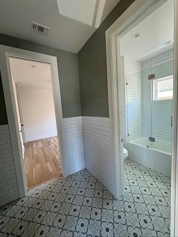 5800 Goodwin Avenue Dallas, TX 75206 - Photo 37 of 39 The bathroom features patterned tile flooring, subway tile walls, and a bathtub with a clear glass enclosure