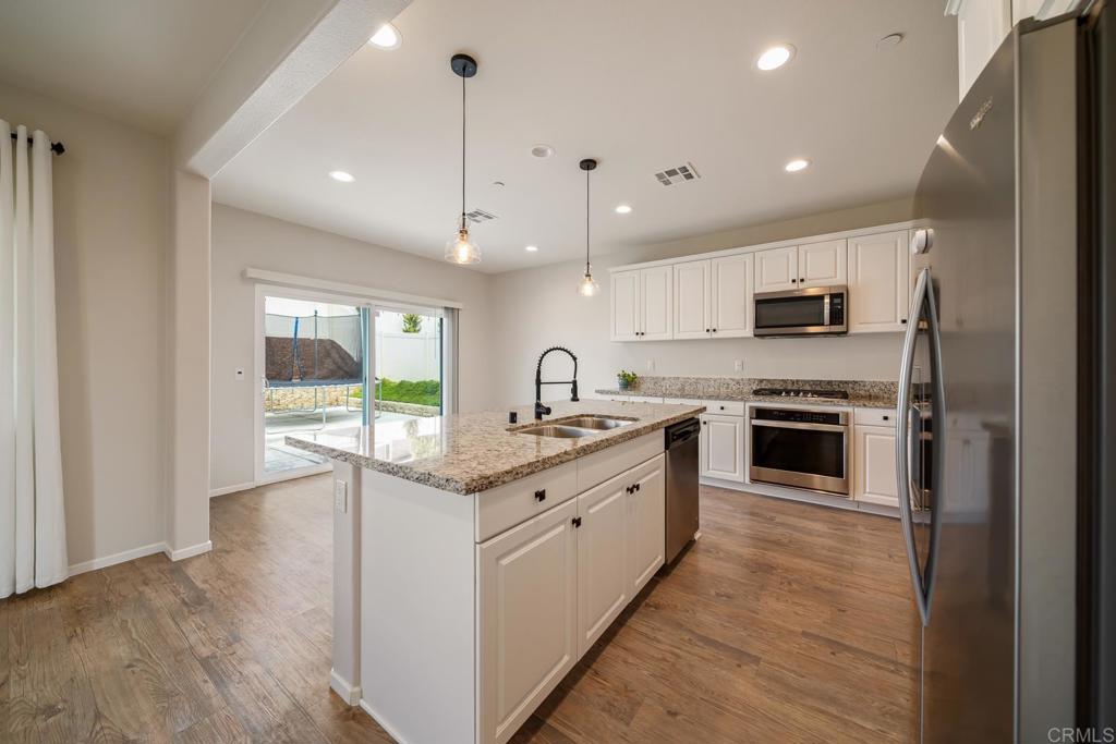352 Misaki Way Fallbrook, CA 92028 - Photo 12 of 68 a large kitchen with stainless steel appliances granite countertop a sink and cabinets