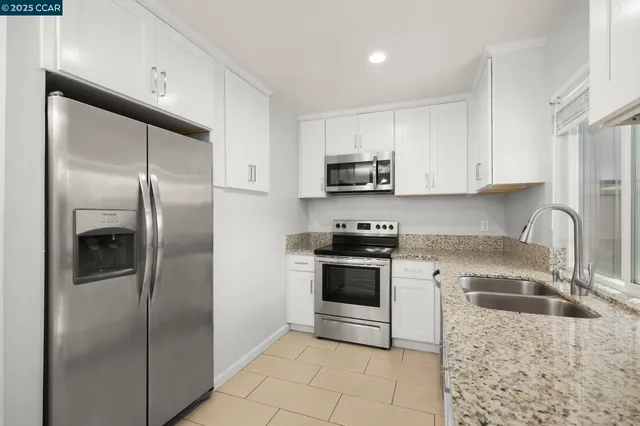 a kitchen with stainless steel appliances granite countertop a refrigerator a stove a sink and a microwave