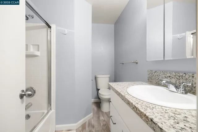 a bathroom with a granite countertop sink a toilet and bathtub